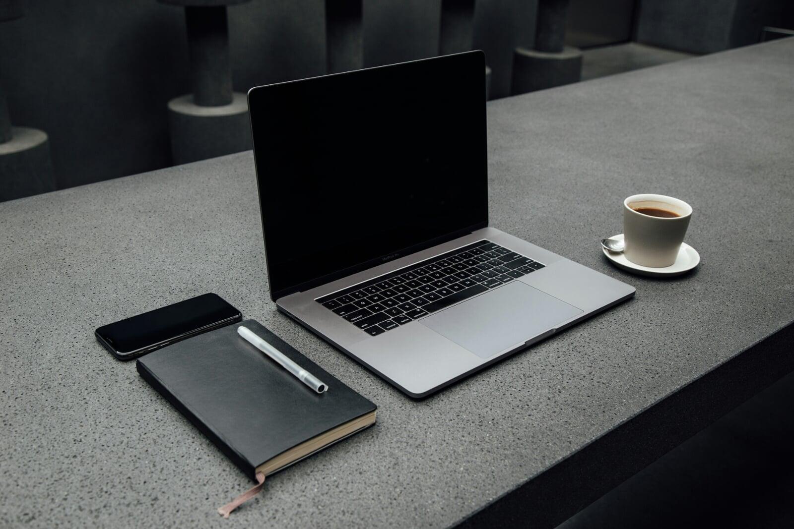 desk with smartphone, notebook, laptop, and coffee